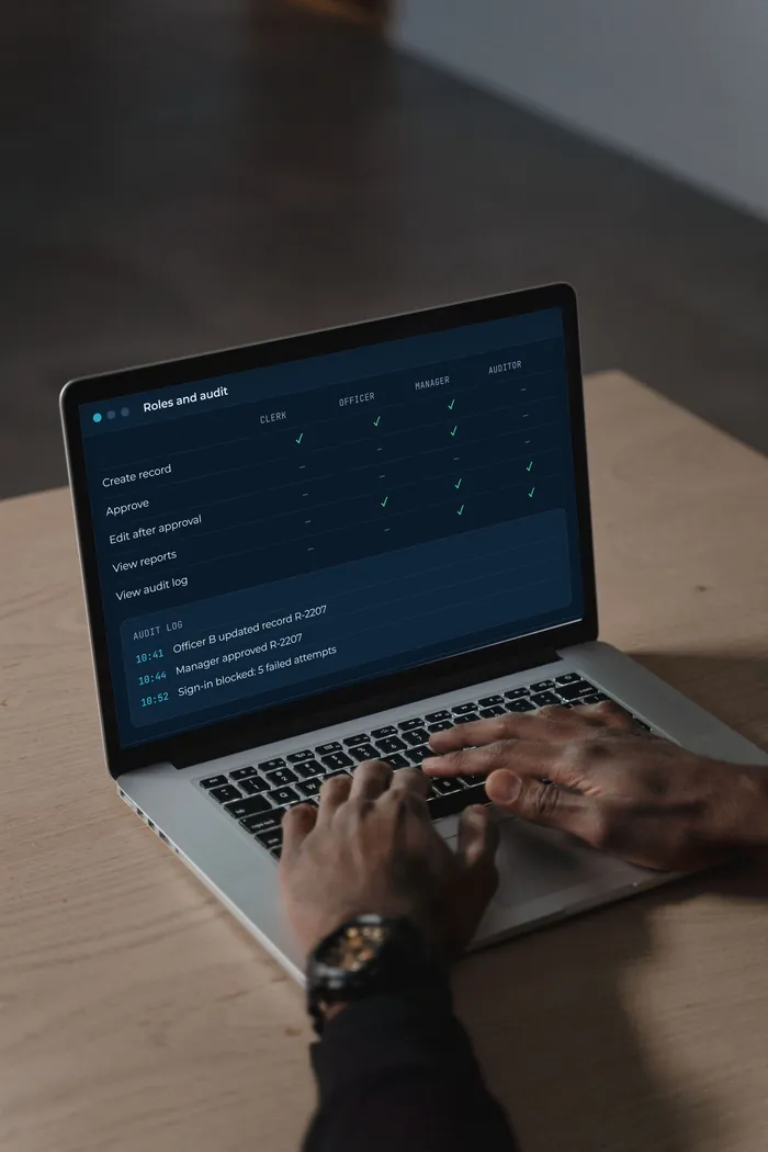 A laptop showing a role permission matrix and audit log with sample data.