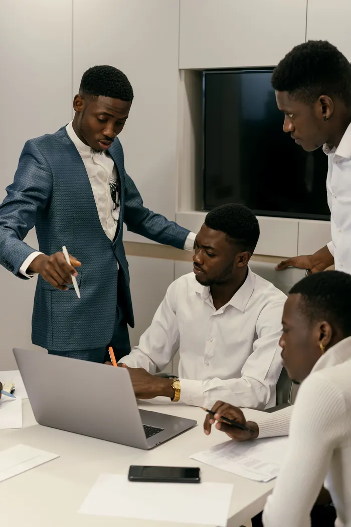 A colleague explaining a plan to two others at a laptop.